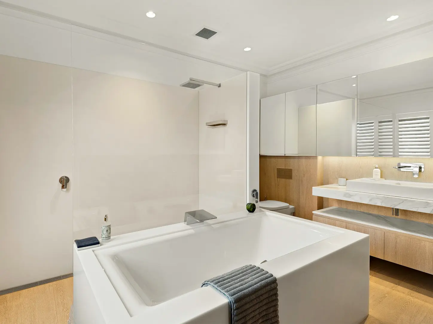 Vraie salle de bains lumineuse avec baignoire, douche, vasque et robinetterie chromée